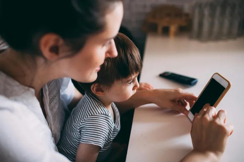 A parent and child looking at a phone together at home